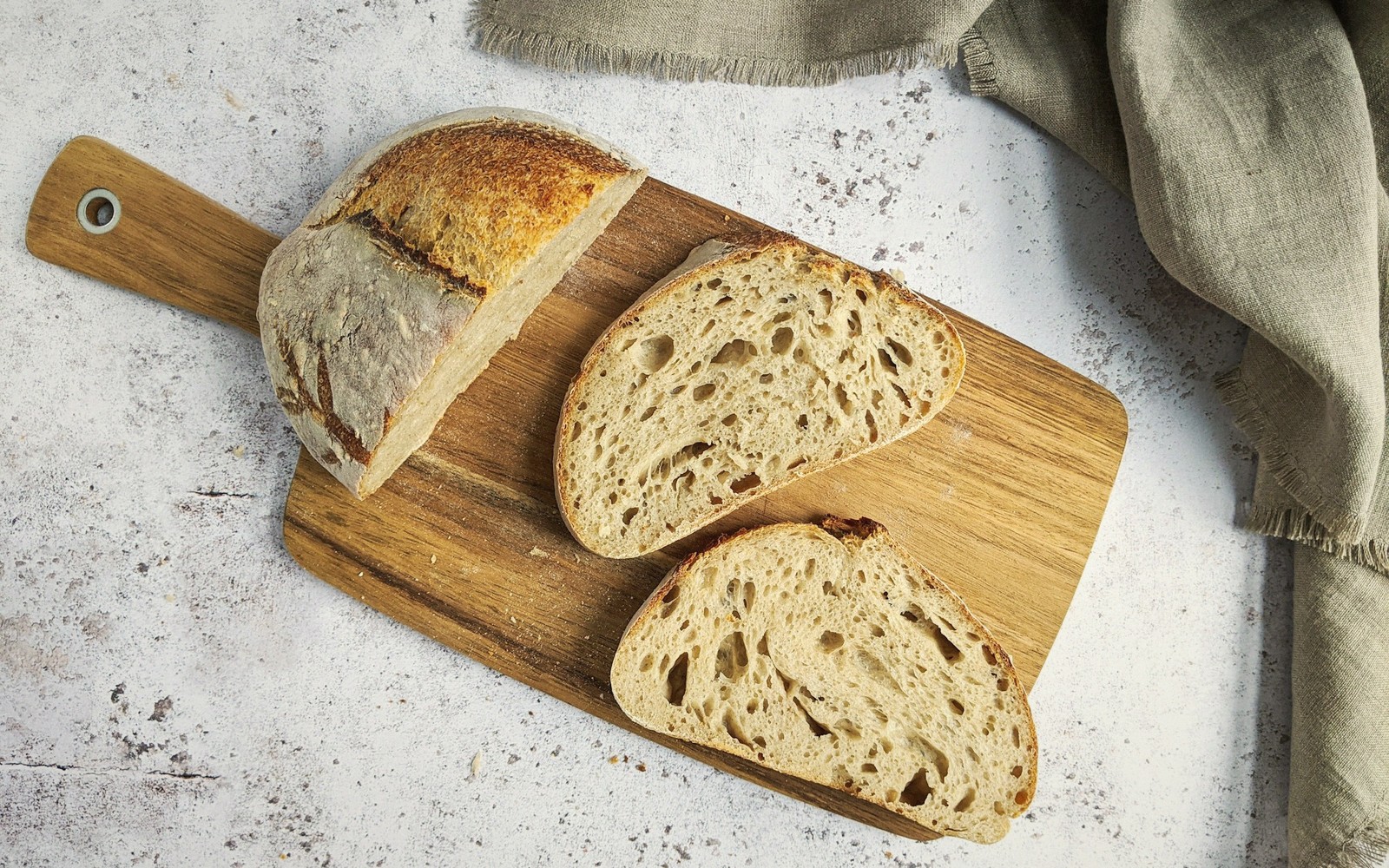 Sliced sourdough loaf with an open crumb on a wooden cutting board